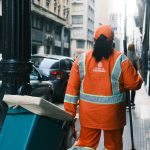 Trabalhador da limpeza urbana carrega equipamentos em uma rua de São Paulo.