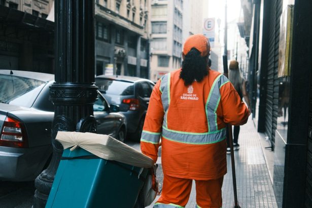Trabalhador da limpeza urbana carrega equipamentos em uma rua de São Paulo.