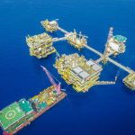 Vista aérea de um complexo de plataformas de exploração offshore em alto-mar.