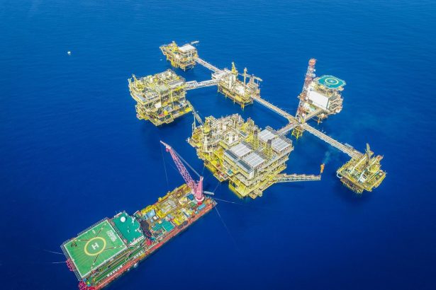 Vista aérea de um complexo de plataformas de exploração offshore em alto-mar.