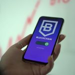 Mão segura um smartphone que exibe uma carteira digital de criptomoedas com interface de blockchain.