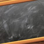 Quadro-negro vazio de uma sala de aula, com marcas de giz