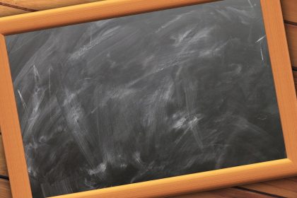 Quadro-negro vazio de uma sala de aula, com marcas de giz