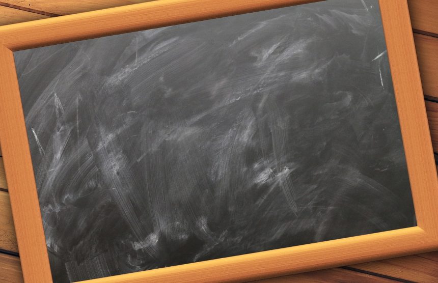 Quadro-negro vazio de uma sala de aula, com marcas de giz