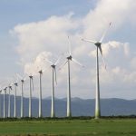 Aerogeradores de um parque eólico em uma paisagem aberta sob o céu claro.